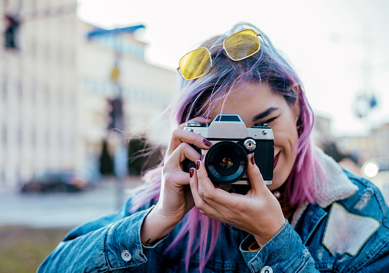 A young person holding up a camera taking a photo for the Feel Out Loud Community Creator Space at Kids Help Phone