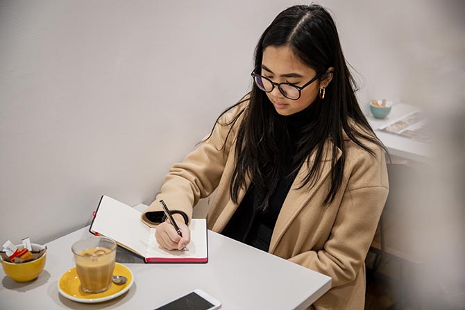 Young person sitting at a table writing in a notebook