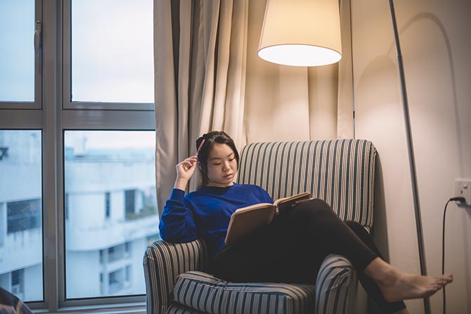 Young person sitting in a chair by the window with a notebook