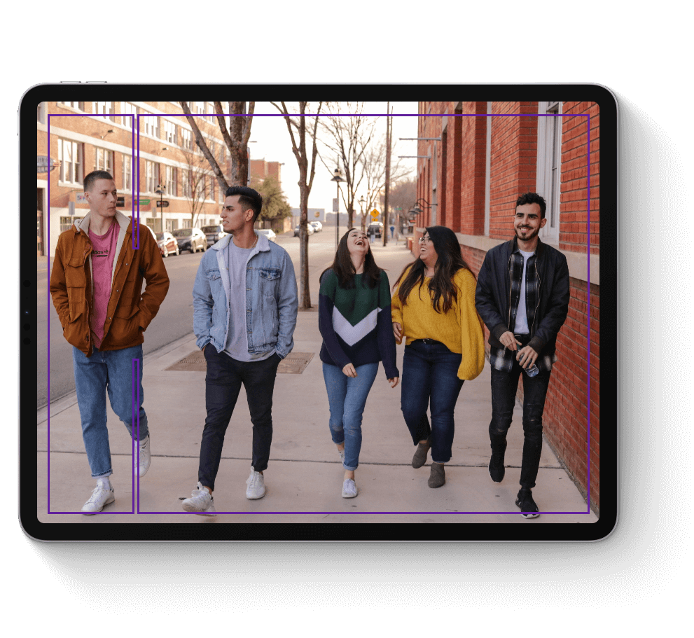 A group of male and female youth walking down the street smiling and laughing.